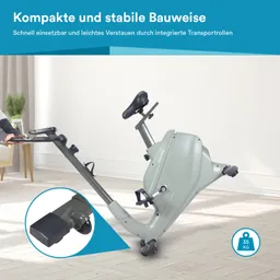 Das Bild zeigt ein kompaktes, hellgraues Fahrradergometer mit einem stabilen Rahmen. Es verfügt über einen Sattel, Pedale und einen Haltegriff. Im Vordergrund ist ein detaillierter Blick auf einen der Transportrollen zu sehen.