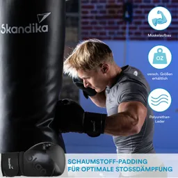 Mann mit sportlichem Oberteil und Boxhandschuhen schlägt einen Boxsack. Hintergrund zeigt eine Trainingsumgebung.