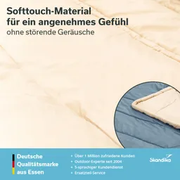 Beige Decke aus Softtouch-Material mit einem blauen Rand, auf einem hellen Untergrund liegend. Textinformationen enthalten.