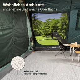 Zeltinnenseite mit grünen Wänden, schwarzem Stuhl, Tisch und einem Fenster mit Blick auf eine grüne Landschaft.