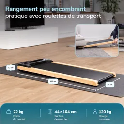 Laufband mit Holzrahmen, liegend auf einem Teppich. Maße und Gewichtsangaben sind sichtbar. Hintergrund zeigt einen Raum mit Fernseher.