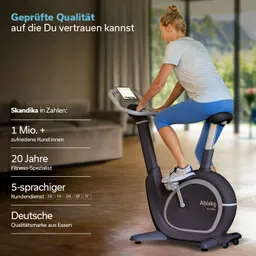 Fahrrad mit EMS-Bremssystem und LED-Anzeige steht in einem modernen Raum. Eine Person sitzt darauf und trainiert.