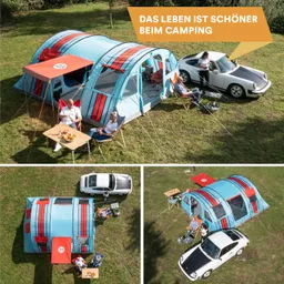 Zelt in bunten Farben auf einer Wiese, zwei Personen sitzen an einem Tisch, daneben zwei Autos.