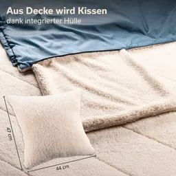 Beige Kuscheldecke und Kissen auf einem Bett, Kissen mit Maßen in cm angezeigt. Decke hat eine glatte Oberseite.