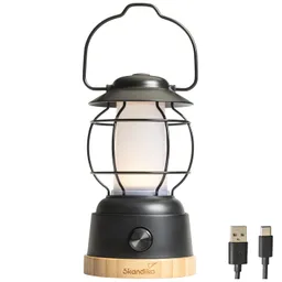Kabellampe in Form einer Laterne mit schwarzem Metallgitter, Holzsockel und USB-Kabel rechts.