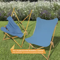 Zwei Klappstühle aus Holz mit hellblauem Baumwollbezug auf einer grünen Wiese, im Hintergrund Blumen.