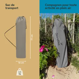 Grauer Transportbeutel mit Maßen 77 cm x 18 cm und einem Gewicht von 3,3 kg, umgeben von Pflanzen und einem Zaun.