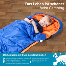 Ein Kind liegt in einem blauen Schlafsack mit orangefarbenem Innenfutter auf einem Holzfußboden.