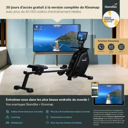 Rudergerät von Skandika mit Monitor und Smartphone in einem modernen Raum. Im Hintergrund ein Fernseher mit einer Trainingsvideoansicht.
