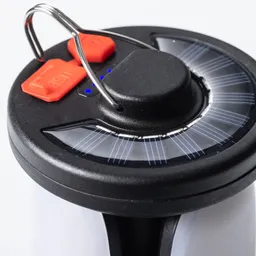 Oberseite eines schwarzen Geräts mit solarbetriebenen Elementen, roten Tasten und einer Metallschlaufe.