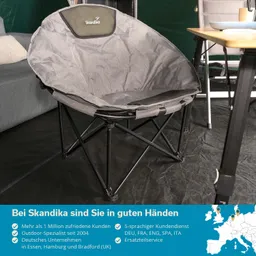 Grauer, runder Faltstuhl mit schwarzem Rückenpolster, neben einem Sofa und einem Tisch in einem Zelt, mit Informationen zur Marke.