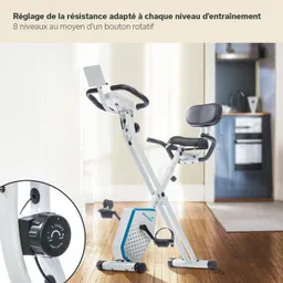 Fahrrad-Ergometer mit verstellbarem Sitz und Widerstandsregler. Im Hintergrund eine moderne Küche. Holzfußboden.