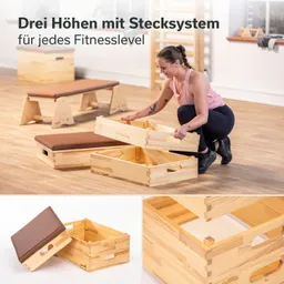 Fitnessgeräte aus Holz in verschiedenen Höhen. Person montiert Teile in einem Trainingsraum mit Holzboden.