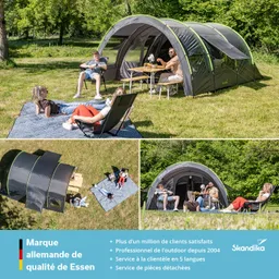 Zelt in grüner Wiese mit vier Personen, die auf Liegestühlen und einer Decke sitzen. Tisch neben dem Zelt.