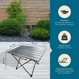 Klappbarer Tisch aus eloxiertem Aluminium auf einer Holzterrasse, umgeben von grünen Sträuchern und einer Holzwand.