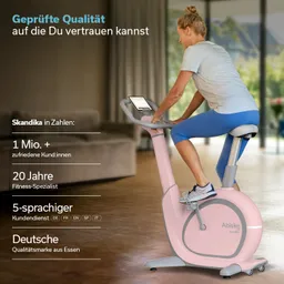 Stationäres Fahrrad in einem hellen Raum, genutzt von einer Person. Das Gerät ist pink und grau, mit einem digitalen Display.