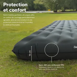Schwarzes, aufblasbares Luftbett mit strukturiertem Bezug, auf einer grünen Wiese. Nahaufnahme eines Teils des Bettes.