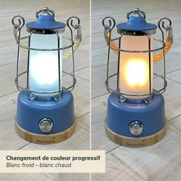 Tischlampe in blauer Farbe mit korbähnlichem Metallgitter und einem Holzsockel. Links leuchtet eine kalte Lichtfarbe, rechts warm.