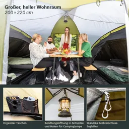 Im Zelt sitzen vier Personen an einem Tisch. Der Innenraum ist hell und geräumig, mit einem Tisch, Stühlen und Taschen. Oben hängt eine Lampe. Am Zeltboden sind Schlafmöglichkeiten erkennbar.
