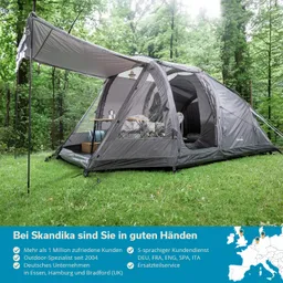 Graues Zelt auf einer Wiese im Wald, mit einem Tisch und Stühlen im Inneren. Bäume im Hintergrund.