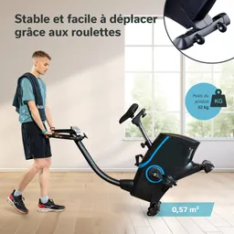 Ein Fitnessgerät wird von einer Person getragen. Das Gerät hat Räder und steht in einem hellen Raum mit Fenstern.