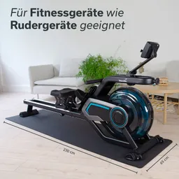 Rudergerät auf einer schwarzen Unterlage in modernem Raum mit Holzfußboden, Couch und Pflanze im Hintergrund.
