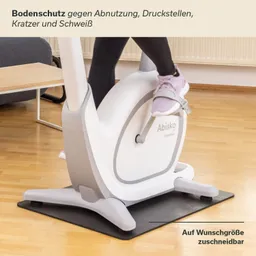 Bodenschutzmatte unter einem Fitnessgerät, Teppichboden, Fuß einer Person auf dem Gerät, neutraler Hintergrund.