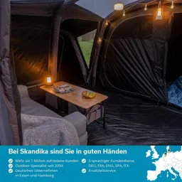 Die Innenseite eines Zeltes mit einem Sofa, einem Tisch und einer Lampe. Auf dem Tisch liegen Bücher und Obst.