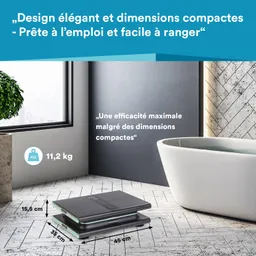 Eine Badezimmerwaage liegt auf einem modernen Boden, daneben steht eine freistehende Badewanne. Ein Fenster mit Ausblick ist im Hintergrund.