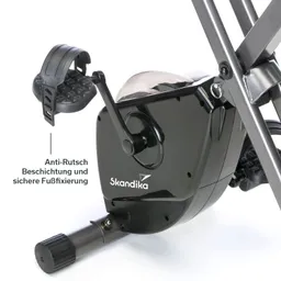 Eine schwarze Fußschlaufe eines Fitnessgeräts mit Anti-Rutsch-Beschichtung. Im Hintergrund ist der Geräteantrieb sichtbar.