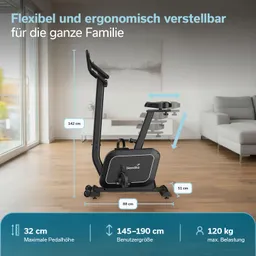 Ergometer in einem Raum mit Holzfußboden. Maße und Spezifikationen sind sichtbar. Sofa im Hintergrund.