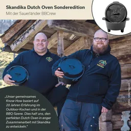 Zwei Personen in schwarzen Oberteilen halten je einen schwarzen Dutch Oven. Im Hintergrund eine Holzstruktur.