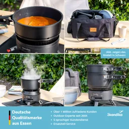 Kochset auf einem Tisch im Freien mit einem Topf, in dem eine Suppe köchelt, und einem schwarzen Tasche, die Geschirr enthält.