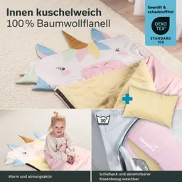 Schlafsack mit Einhorn-Motiv aus hellen Farben und abnehmbaren Kissenbezug auf einem hellen Teppich. Kind sitzt darauf.