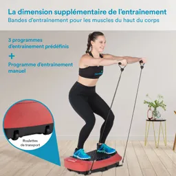 Person steht auf einem roten Trainingsgerät mit Widerstandsbändern, trägt Sportbekleidung und blickt lächelnd nach vorne. Im Hintergrund ein Tisch mit Blumen und Deko.
