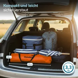Kofferraum eines Fahrzeugs mit einem blauen Kühler, einem Rucksack und einer gestreiften Liege. Ein orangenes, längliches Paket liegt darunter.