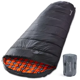 Schlafsack in Schwarz mit kariertem Innenfutter in Orange und einem grauen Packbeutel daneben.