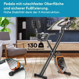 Fahrrad mit rutschfesten Pedalen, stabiler X-Konstruktion und einem Gewichtslimit von 130 kg. Im Hintergrund ein Wohnzimmer.