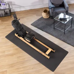 Sitzgerät für das Workout auf einer schwarzen Matte, umgeben von einem Teppich, einem Sessel und einem Beistelltisch.