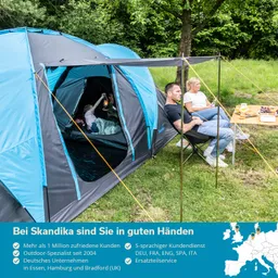 Zelt in der Natur mit offenem Eingang. Eine Person sitzt am Tisch mit Snacks, eine andere sitzt lässig daneben.
