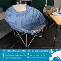 Runder, blauer Stuhl mit Metallgestell, platziert in einem Zelt. Im Hintergrund ein graues Sofa und ein Tisch mit Geschirr.