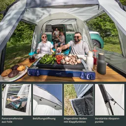 Familie am Tisch im Zelt, mit Grill und frischem Gemüse. Im Hintergrund weitere Personen und ein Fahrzeug.