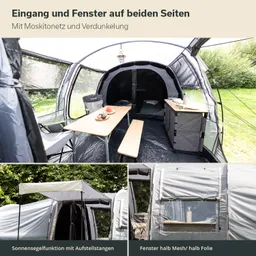 Zeltinneneinrichtung mit Holztisch, Stühlen und Ablagen. Fenster und Eingänge auf beiden Seiten, sichtbare Natur außen.