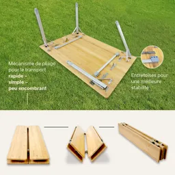 Faltbarer Tisch aus Holz auf einer grünen Wiese, mit einem Mechanismus zur schnellen und einfachen Handhabung, der teilweise auseinandergeklappt ist.