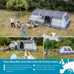 Zelt im Freien mit mehreren Personen, die an einem Tisch sitzen und Essen genießen. Umgebung mit Bäumen und Gras.