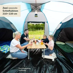 Ein Zelt mit zwei Schlafkabinen. Eine Familie sitzt an einem Tisch mit Getränken und Obst auf einem schwarzen Boden.
