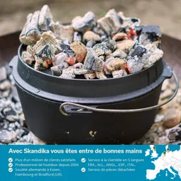 Kessel aus schwarzem Metall mit glühenden Kohlen und Asche, umgeben von Steinen. Heller Hintergrund.