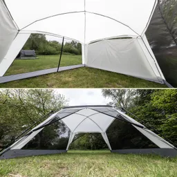 Zelt mit weißen und grauen Wänden, geöffnet mit sichtbarem Innenraum und Fenster. Umgebung aus Gras und Bäumen.