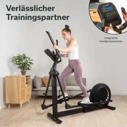 Ellipsentrainer in Wohnraum mit Pflanze, Sofa und Sideboard. Person trainiert auf dem Gerät. Anzeige mit Handpulssensoren.