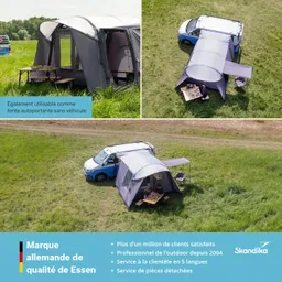 Zelt in grauer Farbe, angelehnt an ein blaues Fahrzeug, auf einer Wiese. Tische mit Stühlen stehen daneben.